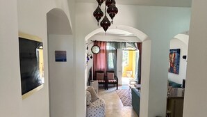 A hallway leading to a living area with a sofa, chairs, and a dining table.