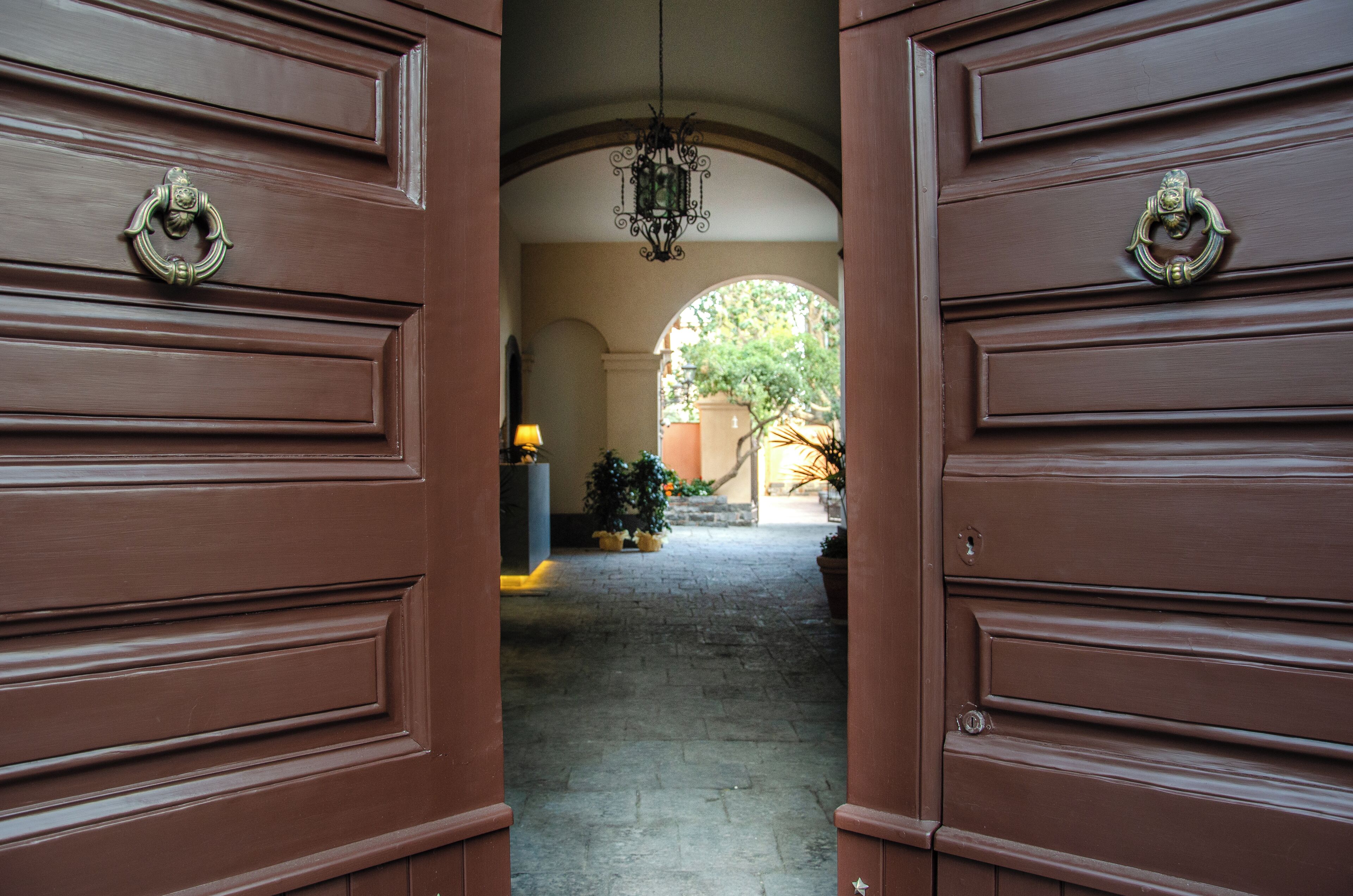 A hallway with a brown door and a hanging light fixture.