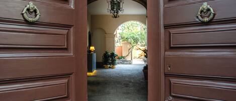 A hallway with a brown door and a hanging light fixture.