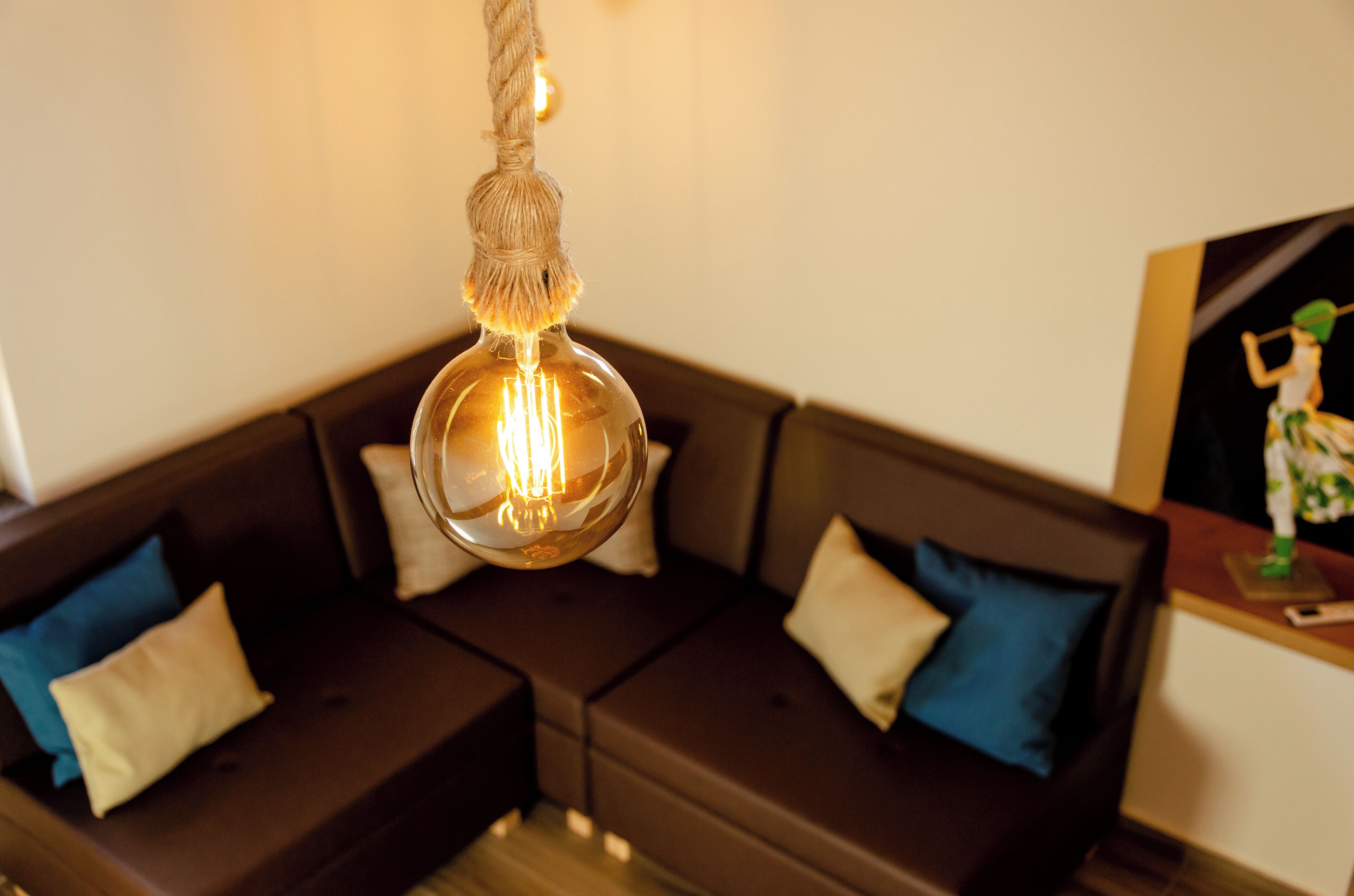 A modern living room with a dark brown sectional sofa, a hanging light fixture, and a small table with a figurine.