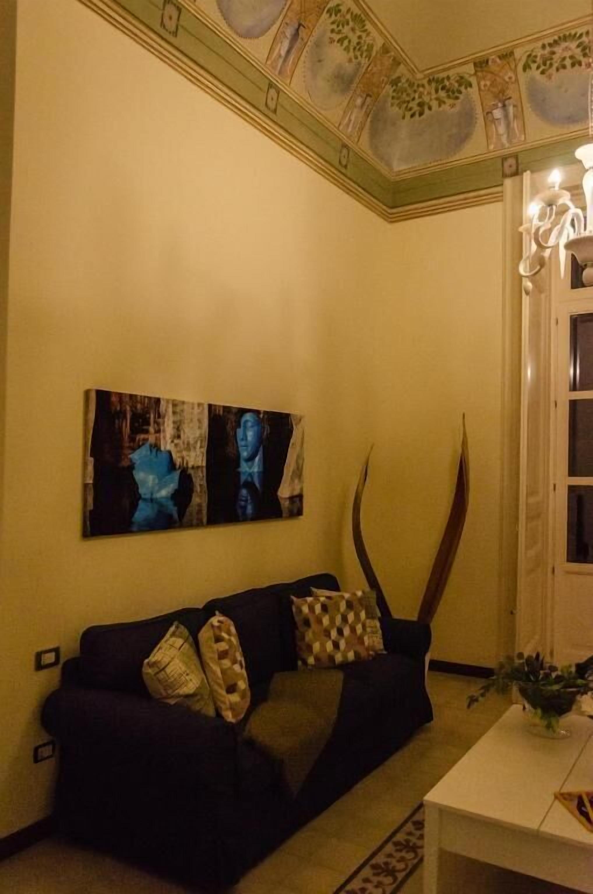 Una sala de estar con un sofá oscuro, una mesa de centro blanca y un cuadro en la pared.