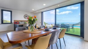 Un comedor moderno con una mesa de madera, sillas y vista al océano.