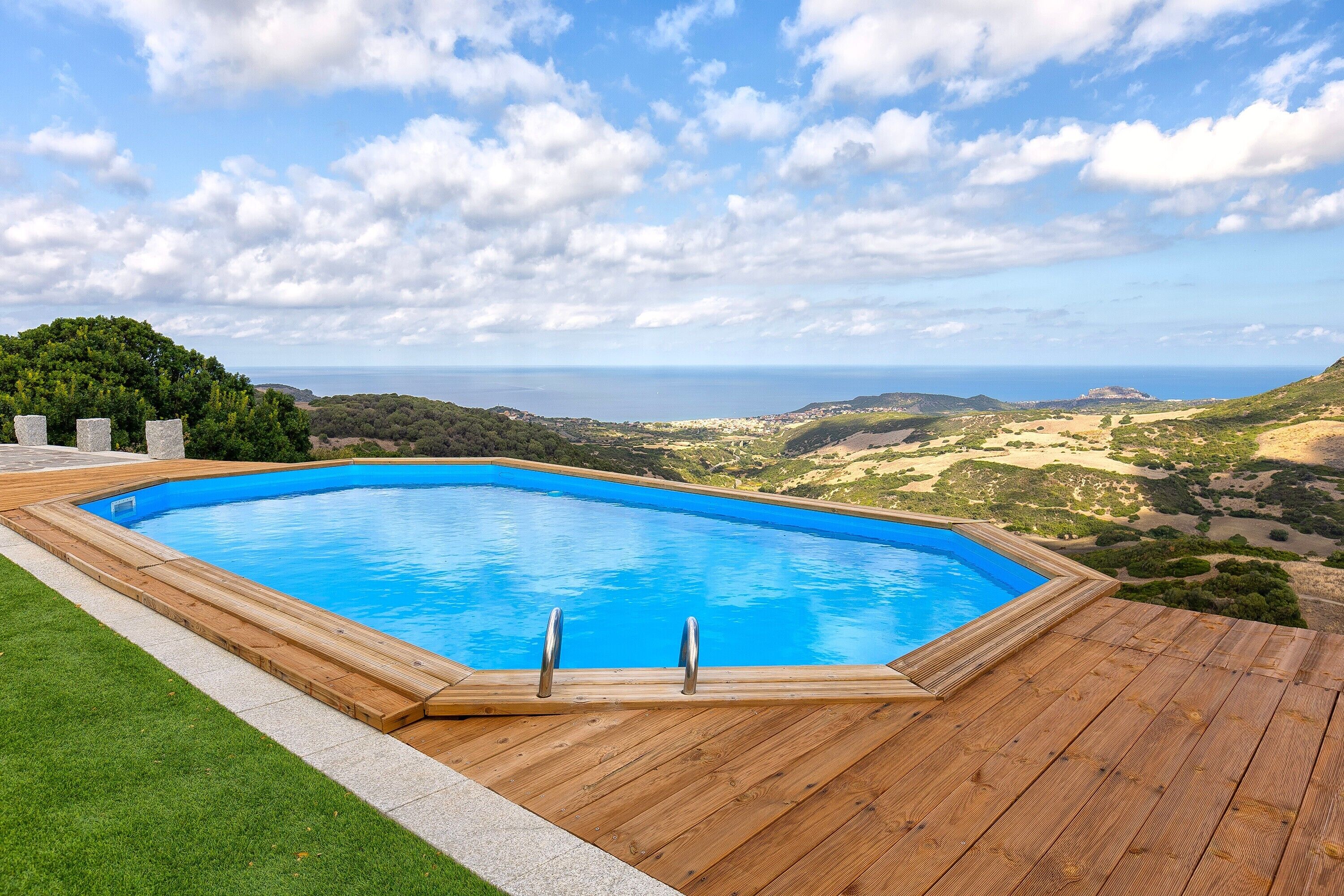A rectangular swimming pool with a wooden deck and a clear blue sky.