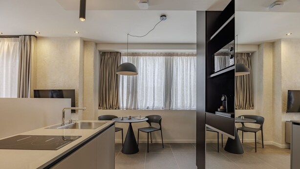 A modern kitchen with a central island, dining area with two chairs, and a built-in TV. - ApartmentsArena - Palazzo Cignaroli® - Il Maestro (Verona)