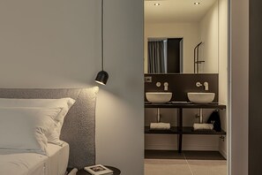 A modern bedroom with a bed, bedside lamp, and a nightstand with a book.
