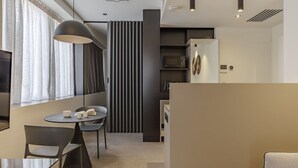 A modern kitchen with a microwave, a refrigerator, and a dining area with a table and chairs. - ApartmentsArena - Palazzo Cignaroli® - Il Maestro (Verona)