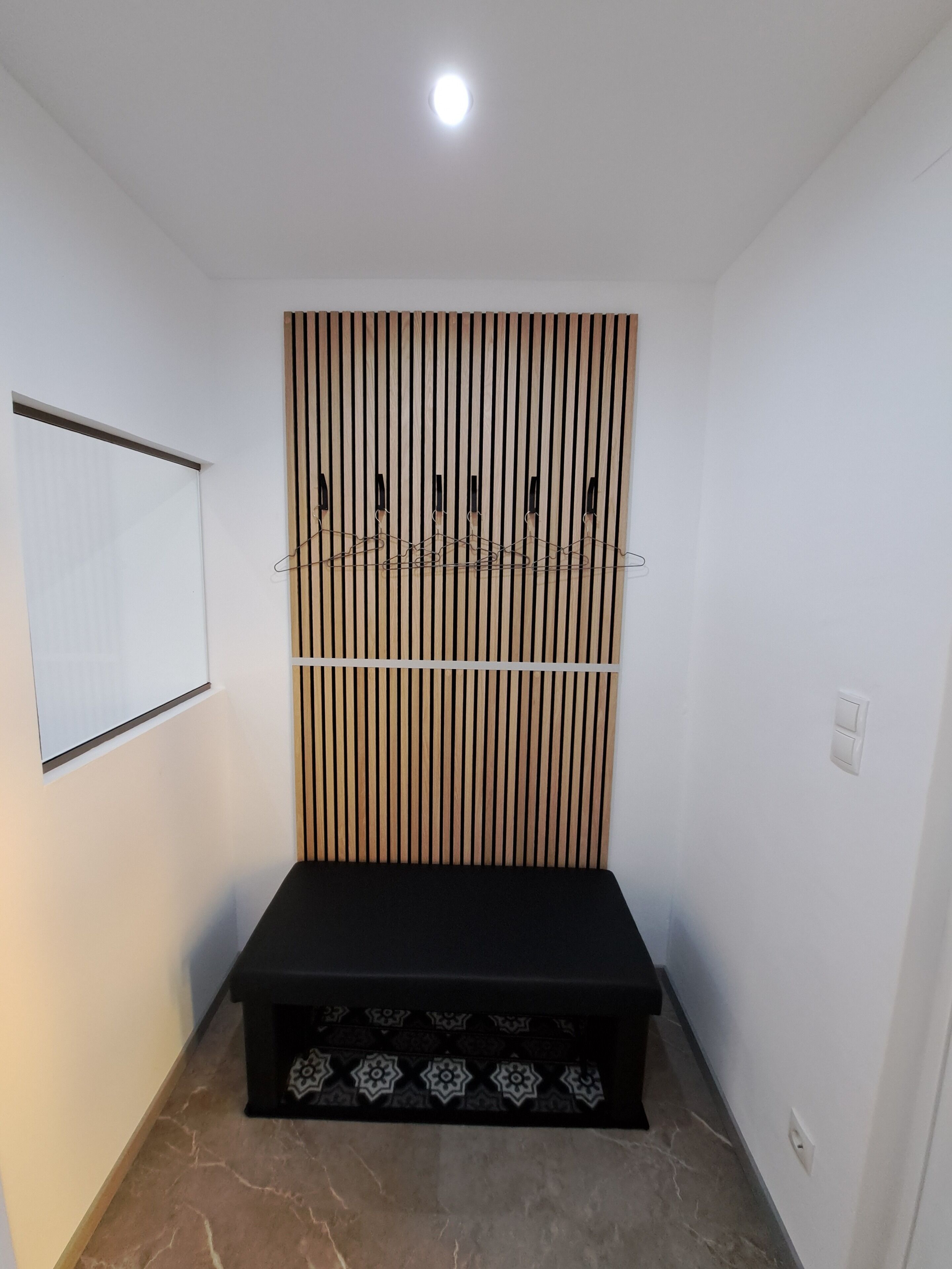 A room with a black bench, a whiteboard, and a wooden slat wall.