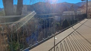 A covered outdoor area with a metal railing, a concrete floor, and a view of trees and hills in the background. - "Vacations on the sunny side of the Semmering in Breitenstein" (Niederösterreich)