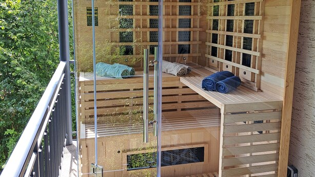 A wooden spa cabin with a glass enclosure, built-in massage tables, and a small outdoor area with a wooden deck. - "Vacations on the sunny side of the Semmering in Breitenstein" (Niederösterreich)