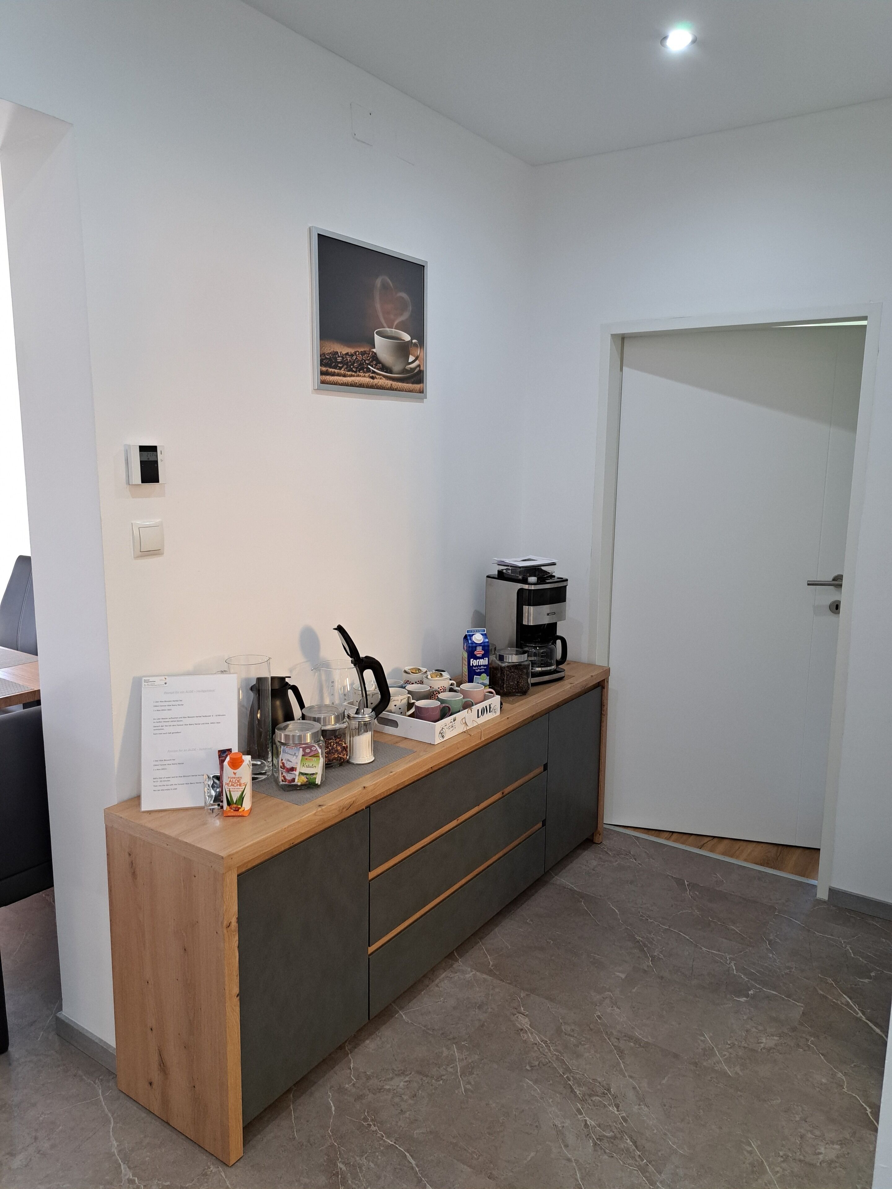A modern kitchen with a wooden countertop, a coffee machine, and various kitchen utensils.