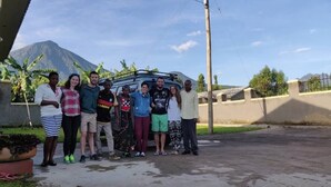 A group of people standing in an outdoor area with a vehicle in the background. - Ikirunga View Homestay Kisoro (Nyarusiza)