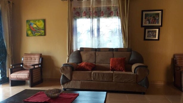 A living room with a sofa, armchairs, a coffee table, and a window with curtains. - Ikirunga View Homestay Kisoro (Nyarusiza)