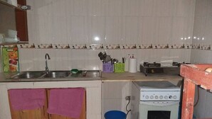 A compact kitchen with a sink, stove, and wooden cabinets. - Ikirunga View Homestay Kisoro (Nyarusiza)