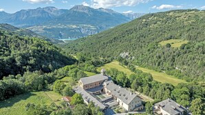A mountainous landscape with a historic building complex featuring multiple structures, surrounded by lush greenery and a valley.