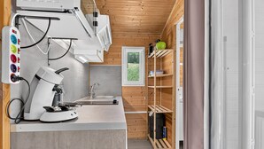 A modern kitchen with a coffee machine, a sink, and wooden shelves.