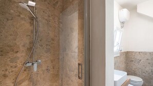 Een badkamer met douche, toilet en wastafel.