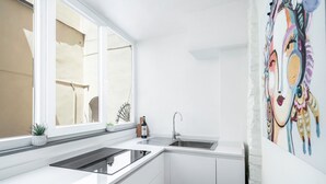 Een moderne keuken met witte kasten, een roestvrijstalen spoelbak en een raam dat natuurlijk licht binnenlaat.