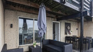 Eine Terrasse im Freien mit einer Couch, Stühlen und einem Tisch.