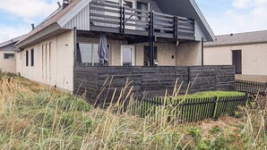 Ein modernes Haus mit Satteldach, Balkon und Holzzaun.