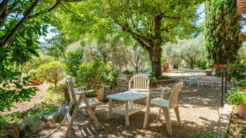 Een terras met een tafel en stoelen, omgeven door bomen en planten.