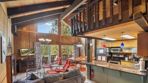 A spacious living area with a large sofa, red chairs, a dining table, and a kitchen with modern appliances.