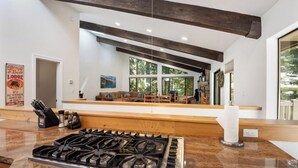 Una cocina moderna con estufa a gas, encimeras de madera y vista a una sala de estar con chimenea.