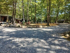 A gravel parking area with trees and a swing set. - TWG - Bunkhouse 3 (Graysville)