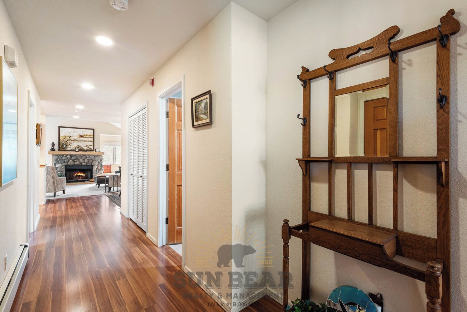 A hallway with wooden flooring, a fireplace, and a mirror with a wooden frame.