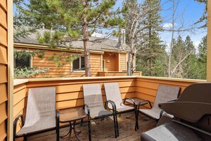 A covered outdoor seating area with four chairs and a table, surrounded by wooden walls and trees. - 2 Bedroom close to Hyatt w Complex Hot Tub (MC154) (Incline Village)
