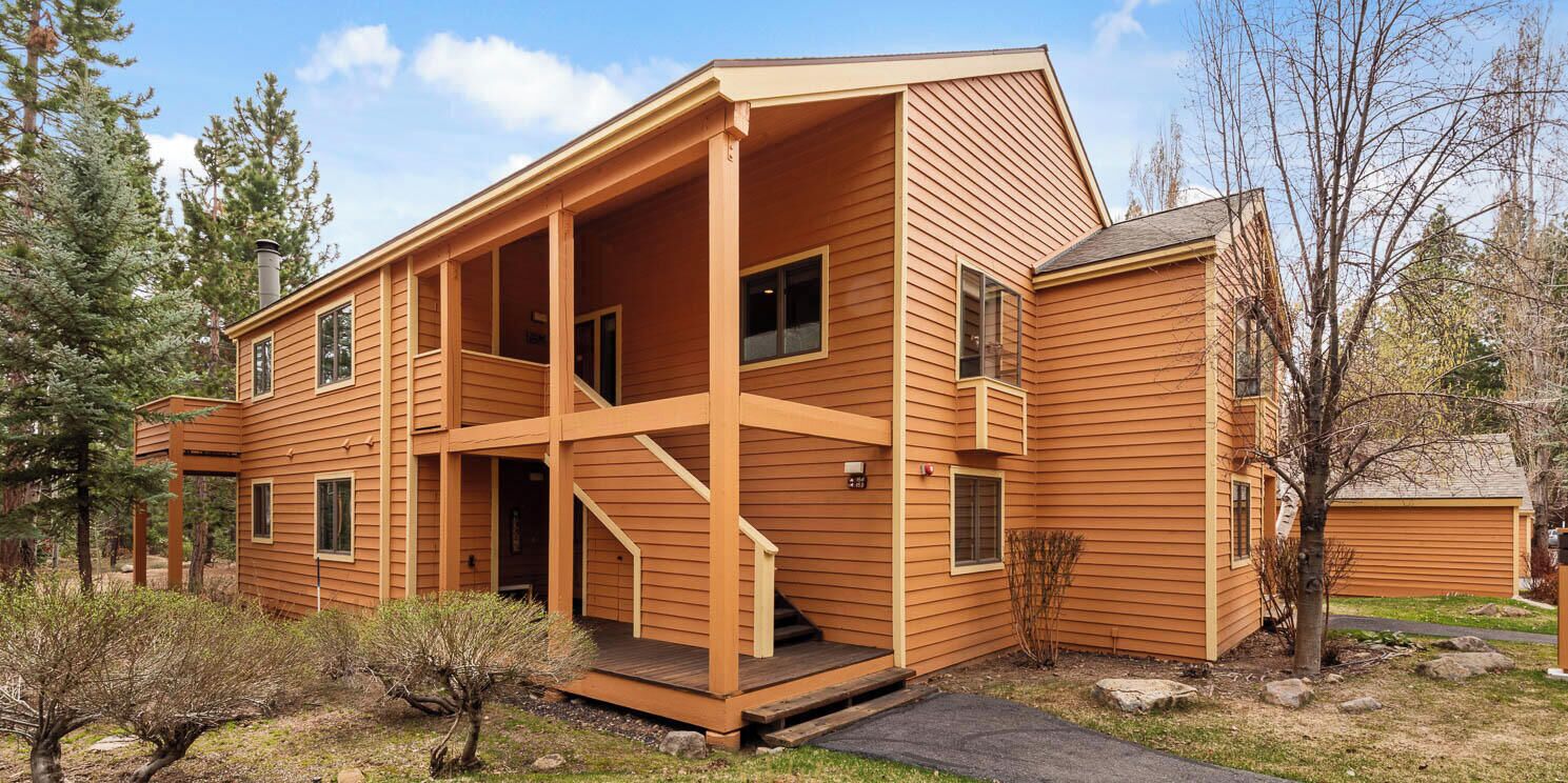 Ein zweistöckiges Holzhaus mit Veranda, Schornstein und kleinem Garten.
