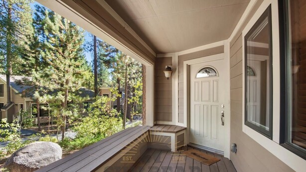 A wooden porch with a bench, a door, and a view of a forested area. - 4 Bedroom w Swimming Pool Close to Hyatt (FP1-24) (Incline Village)