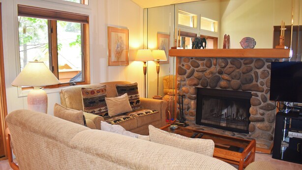 A cozy living room with a stone fireplace, comfortable seating, and a television. - 1 Bedroom close to Hyatt w Complex Hot Tub (MC254) (Incline Village)