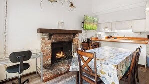 Eine moderne Küche mit Kamin aus Ziegeln, weißen Schränken und einem Essbereich mit Tisch und Stühlen.