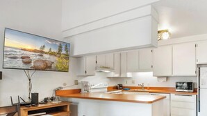 Une cuisine moderne avec des armoires blanches, un plan de travail en bois et un four encastré.