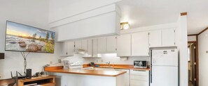 Een moderne keuken met witte kastjes, een houten aanrecht en een ingebouwde oven.
