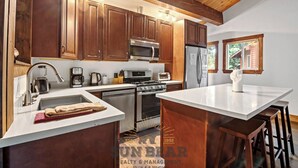 A kitchen with wooden cabinets, stainless steel appliances, a central island, and a window with a view.