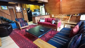 Ein gemütliches Wohnzimmer mit einer Couch, Sesseln, einem Couchtisch und einem Essbereich mit Stühlen und einem Tisch.