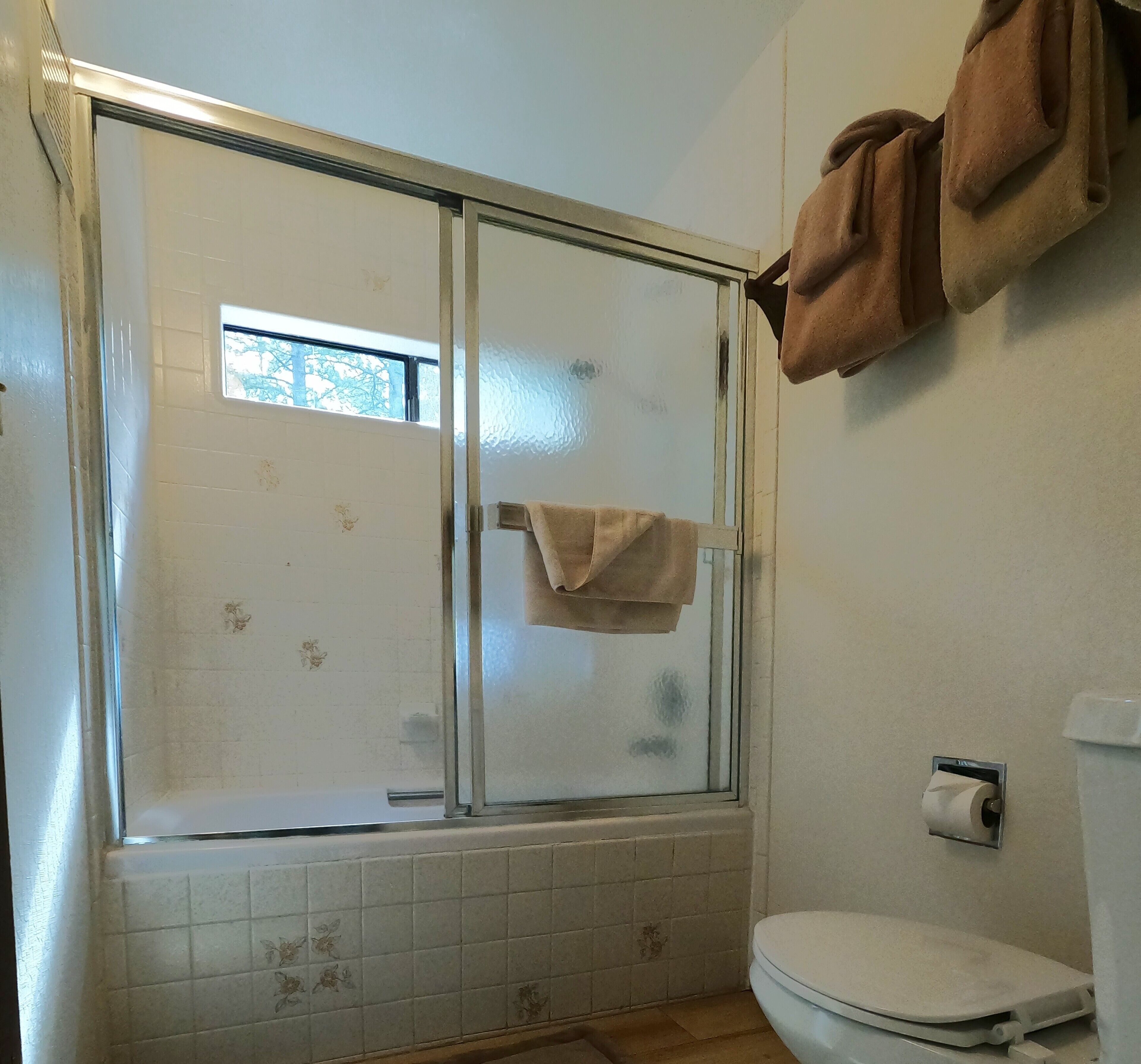 Kylpyhuone, jossa on suihku, wc ja seinälle ripustettu pyyhe.