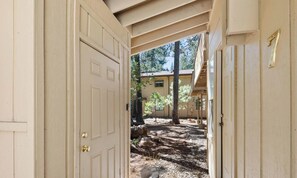 An open door leading to a covered outdoor area with a building in the background.