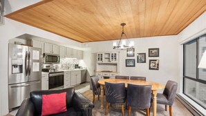 A modern kitchen with stainless steel appliances, a dining area with a wooden table and chairs, and a living room with a leather sofa. - 3 Bedroom w Summer Pool and Hot Tub (FP1-83) (Incline Village)