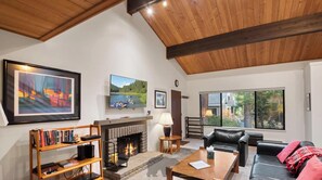A modern living room with a fireplace, a black leather sofa, a coffee table, and a bookshelf. - 3 Bedroom w Summer Pool and Hot Tub (FP1-83) (Incline Village)