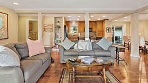 A spacious living room with a grey sofa, a coffee table, and a kitchen in the background.
