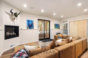 Ein modernes Wohnzimmer mit einer großen Eckcouch, einem Kamin und Kunstwerken an den Wänden.