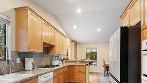 A modern kitchen with wooden cabinets, granite countertops, a built-in stove, and a refrigerator. - 3 Bedroom w Hot Tub and Forest Views (829EL) (Incline Village)