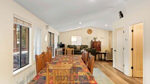 A spacious living area with a dining table, chairs, a sofa, and a television. - 3 Bedroom w Hot Tub and Forest Views (829EL) (Incline Village)
