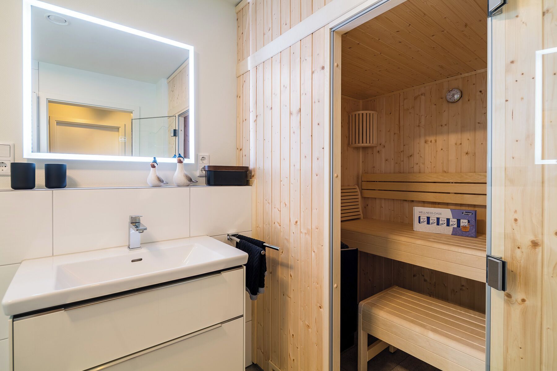A modern bathroom with a white sink, a mirror, and wooden paneling.