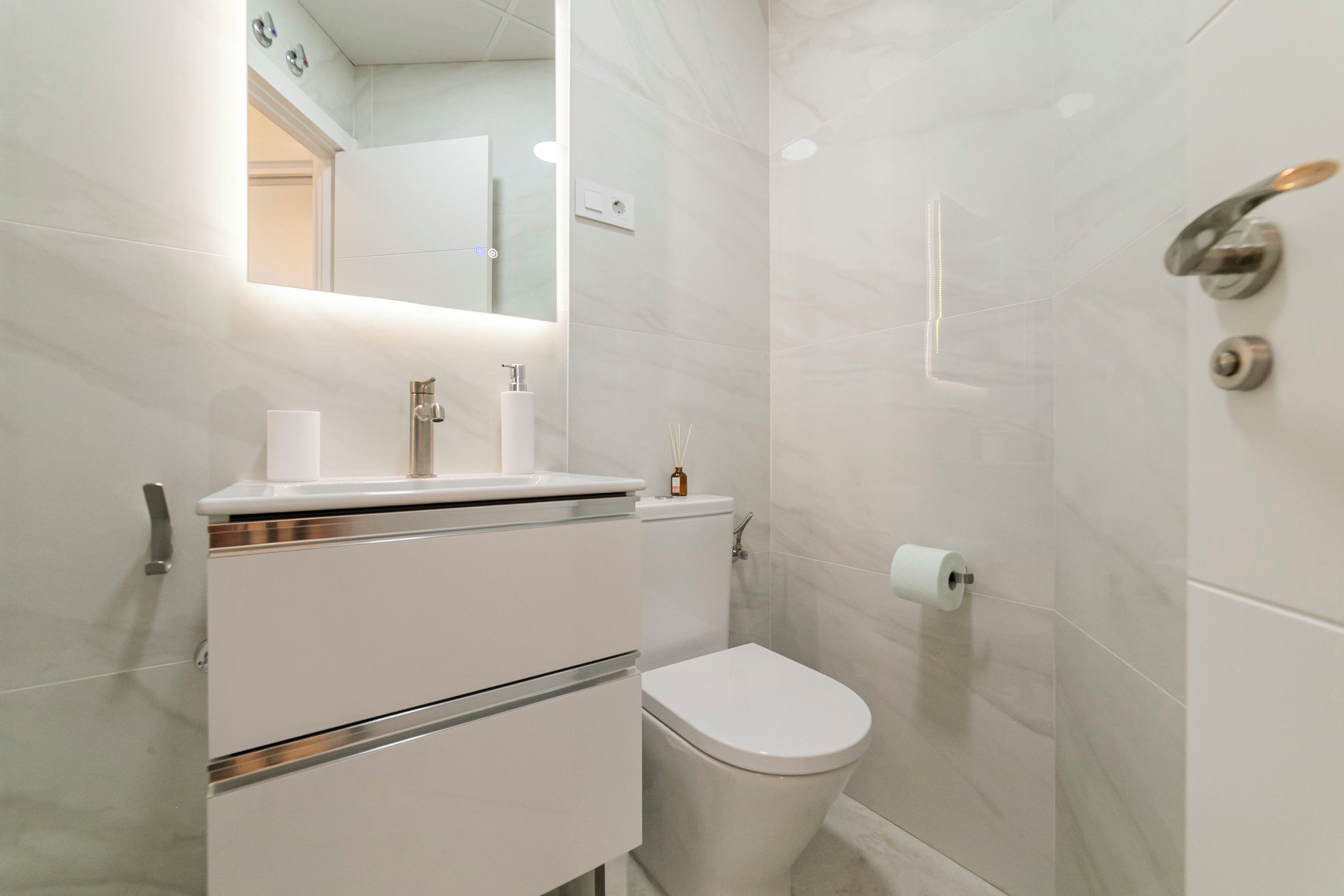 A modern bathroom with a toilet, sink, and mirror.