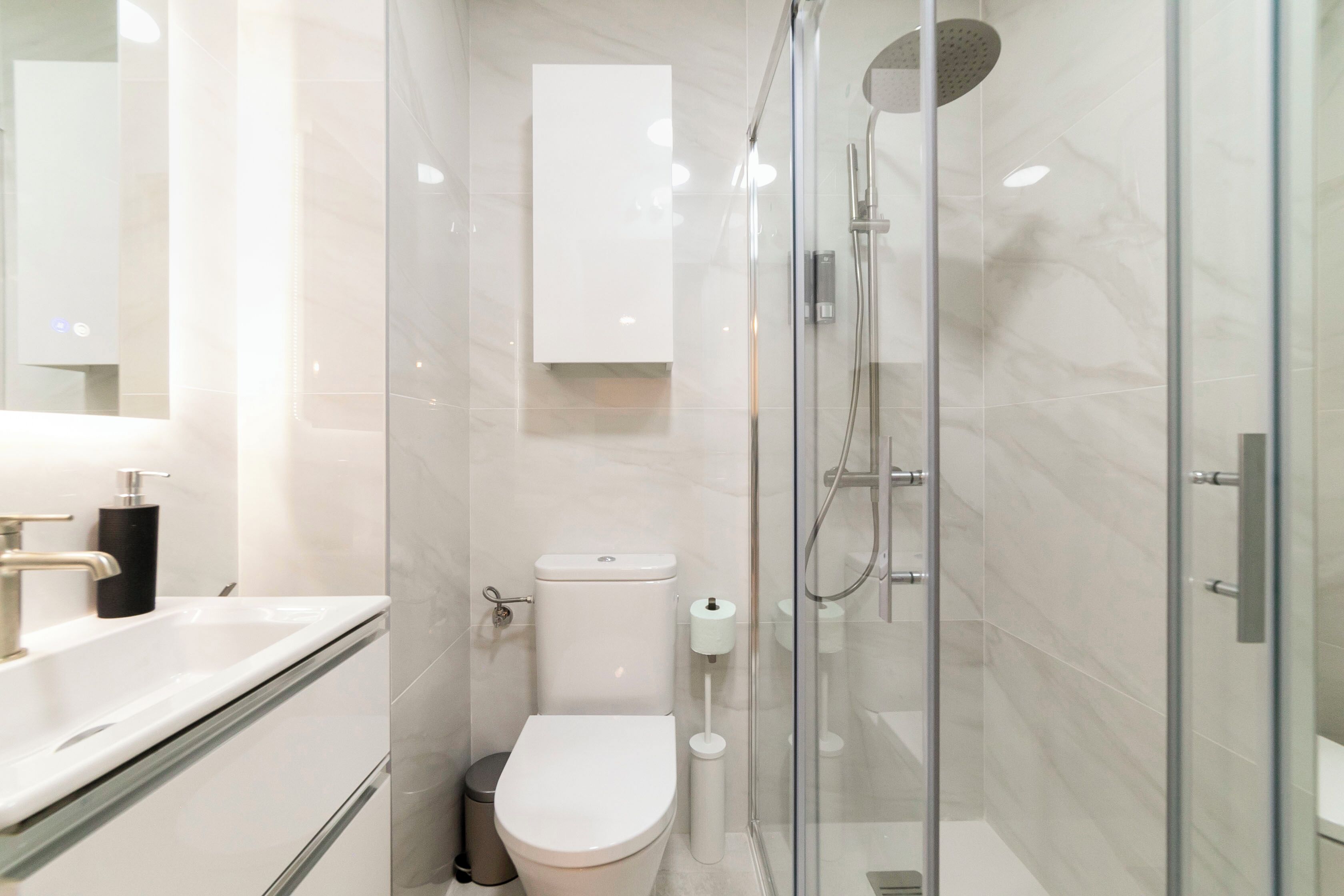 Ein modernes Badezimmer mit einer Duschkabine, einer weißen Toilette und einem Waschbecken mit Armatur.