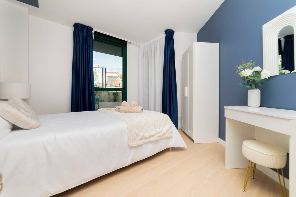 A modern bedroom with a bed, a desk, and a mirror.