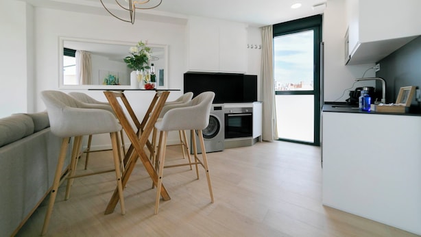 A modern kitchen with a dining area, a washing machine, and a large window.